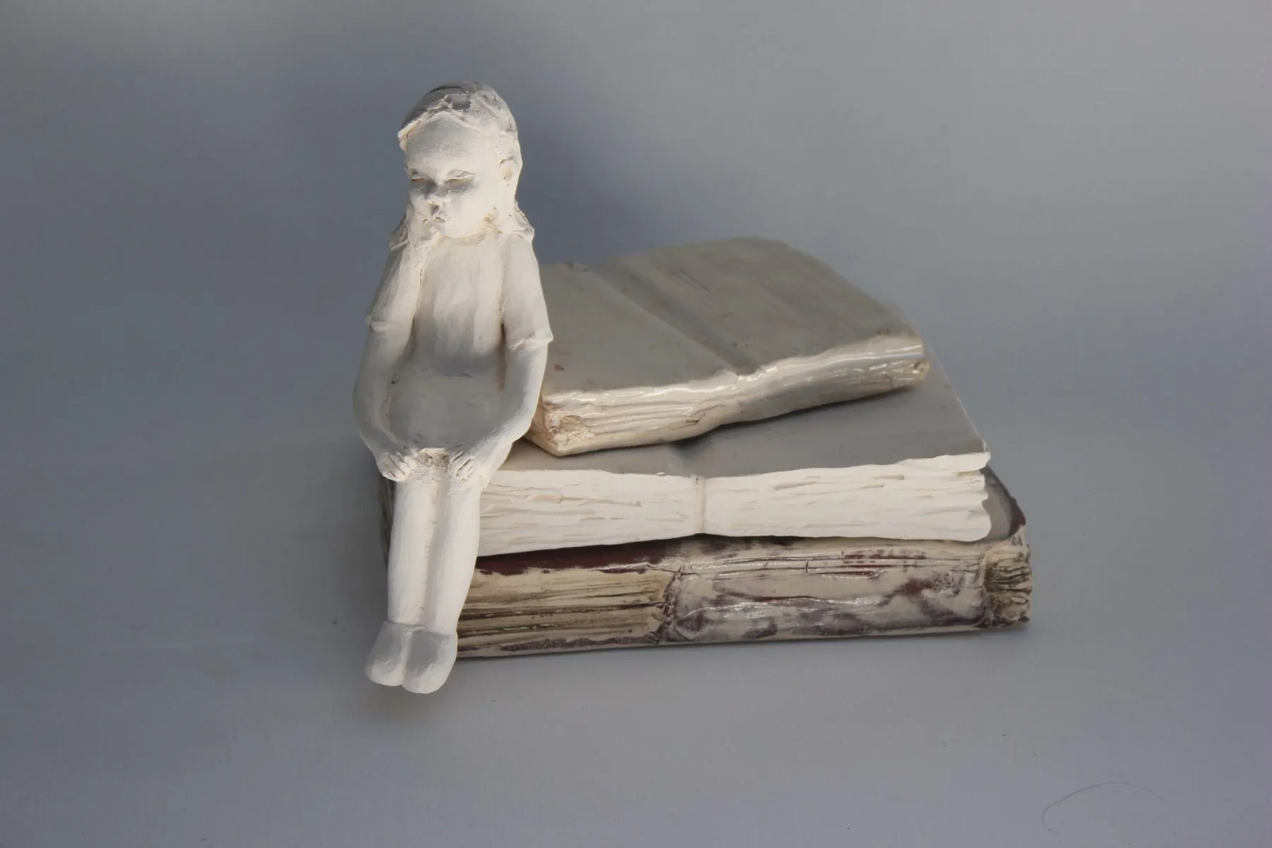 Ceramic girl sitting on a book