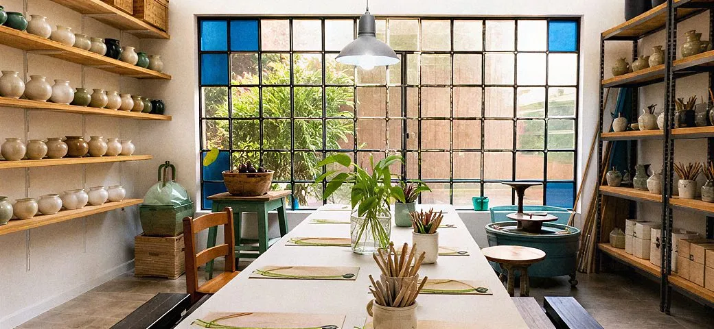 El espacio de Vamos al Taller: mesa larga, estantes con piezas y ventanal