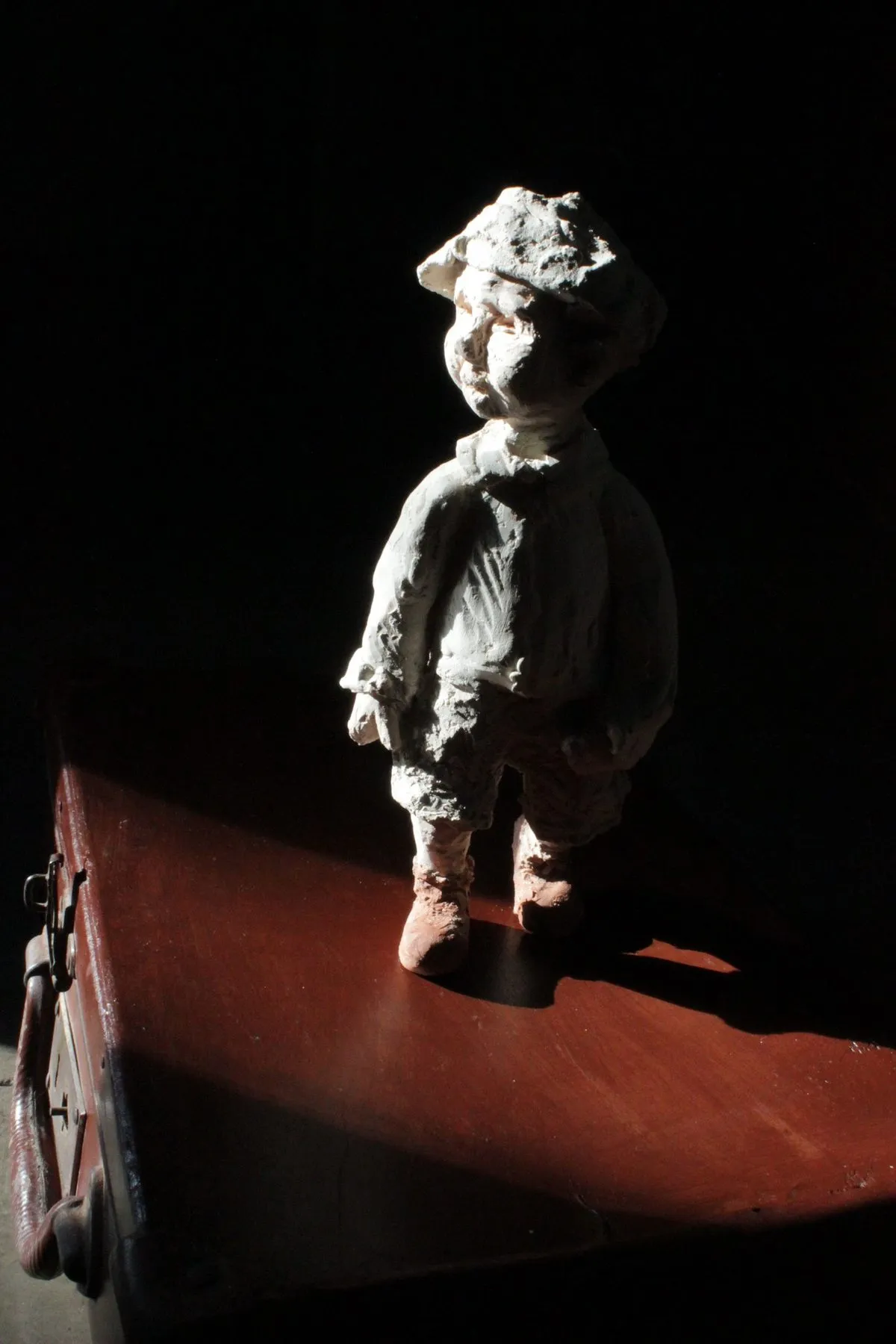 Figure of a boy standing on a red trunk