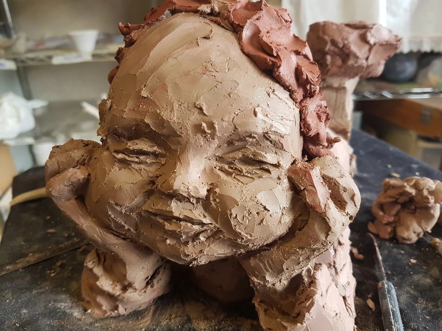 Face of a child in fresh clay, in progress on the studio table