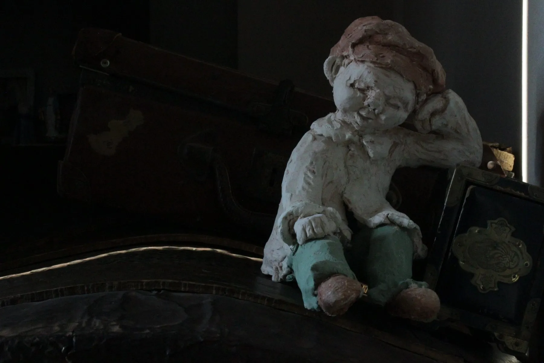 Figure of a seated boy leaning against an old suitcase
